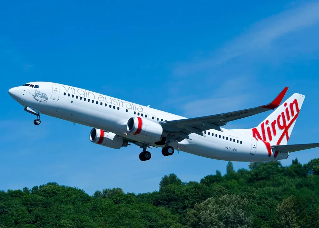 Virgin Australia Boeing 737 passenger airplane climbing into a clear blue sky after takeoff
