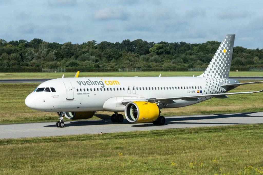 A white Vueling Airlines Airbus A320 passenger airplane with yellow engine