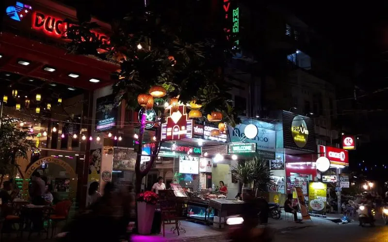 Restaurants and neon lights at night on Phạm Ngũ Lão Street in Ho Chi Minh City.