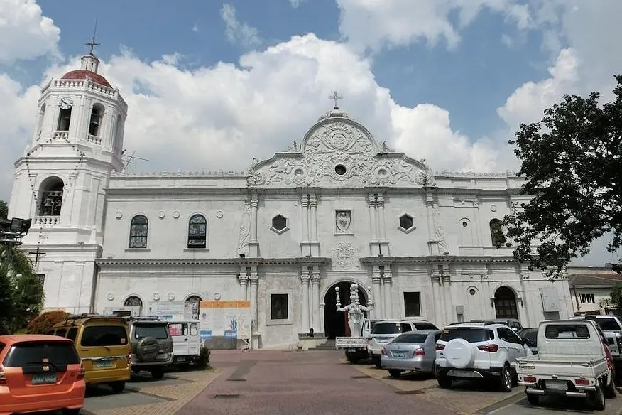 The white facade of the Cebu Metropolitan Cathedral with cars parked in front.