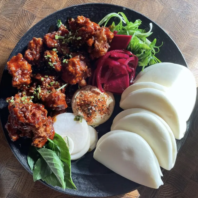 Fried Chicken Steam buns- karaage fried chicken tossed in sweet chili sauce served with kewpie mayo, pickles, scallions and cilantro