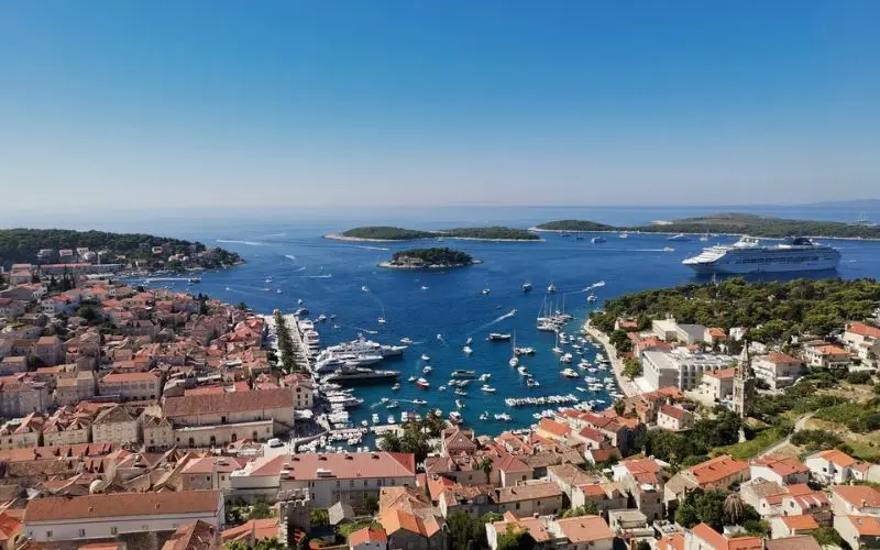 Aerial view of Hvar Island with boats and a cruise ship in the blue Adriatic Sea.