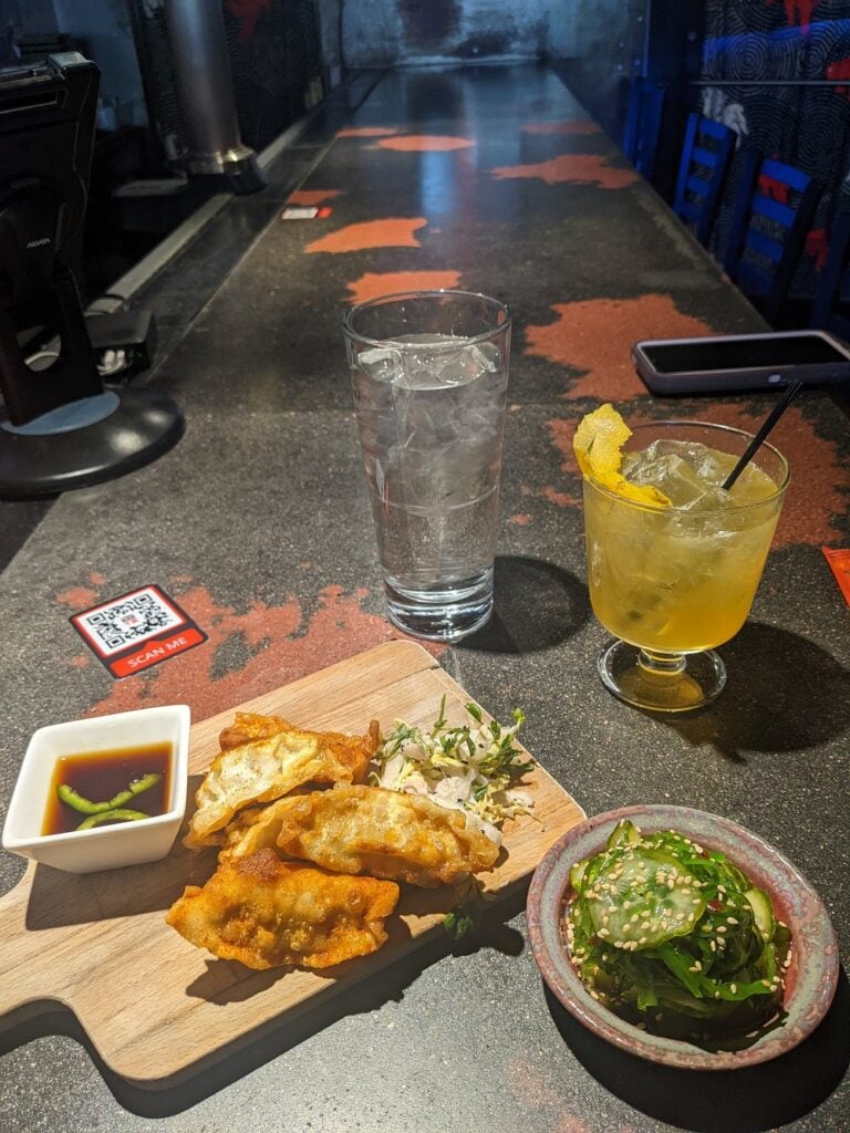 Appetizers and drinks on a dark, artsy bar counter at Chiba Bar.