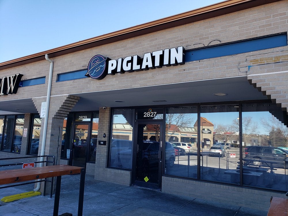 Exterior of Piglatin Cocina with a bold sign above the entrance in a strip mall setting.