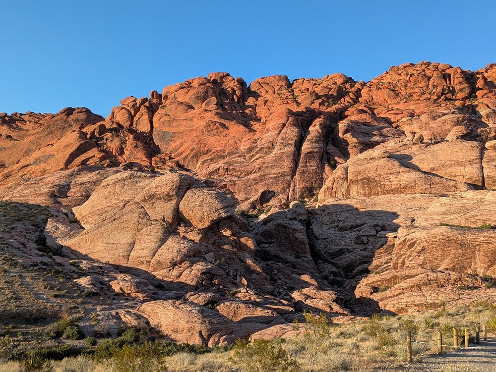 Red Rock Canyon cliffs with rugged red sandstone formations under a clear blue sky.