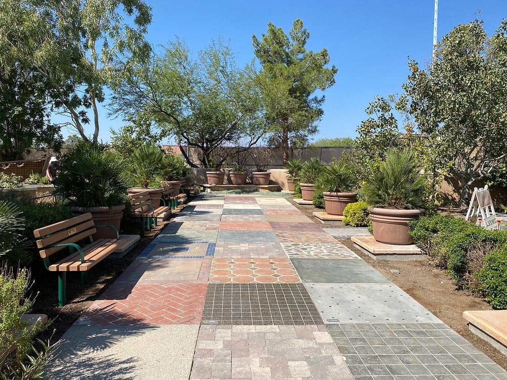 Springs Preserve walkway with patterned tiles, benches, and large potted plants.