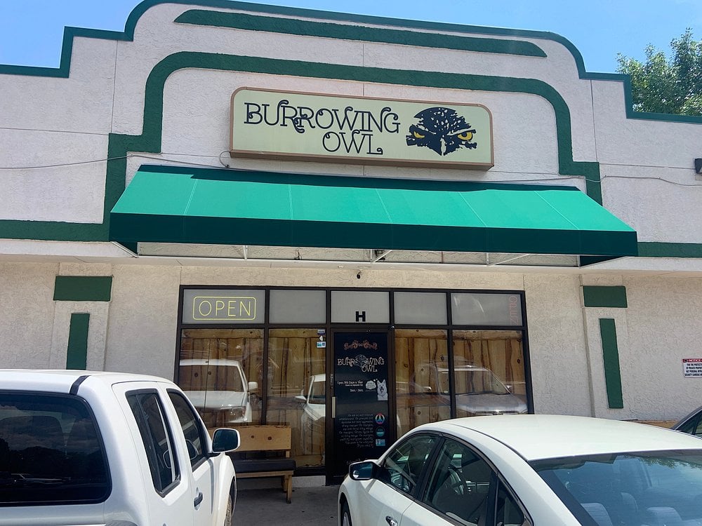 Exterior of The Burrowing Owl with a green awning and a sign featuring an illustrated owl.