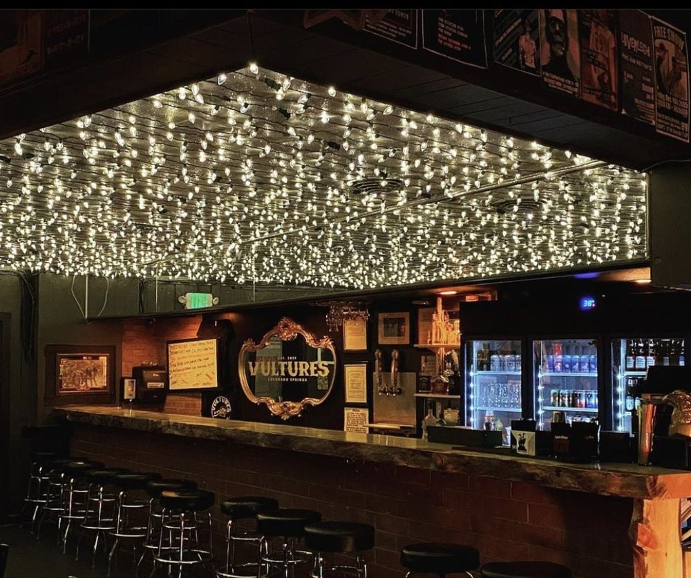Vultures bar with a rustic counter and ceiling covered in glowing string lights.