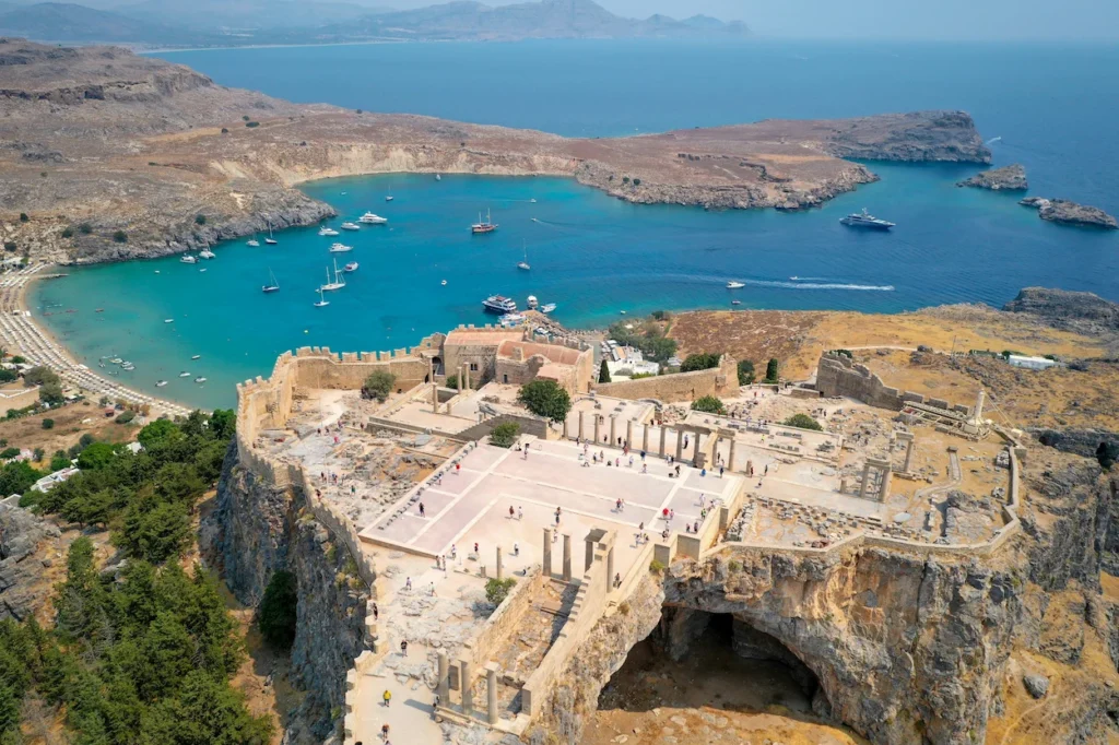 Aerial view of the Acropolis of Lindos in Rhodes overlooking the turquoise waters of Lindos Beach