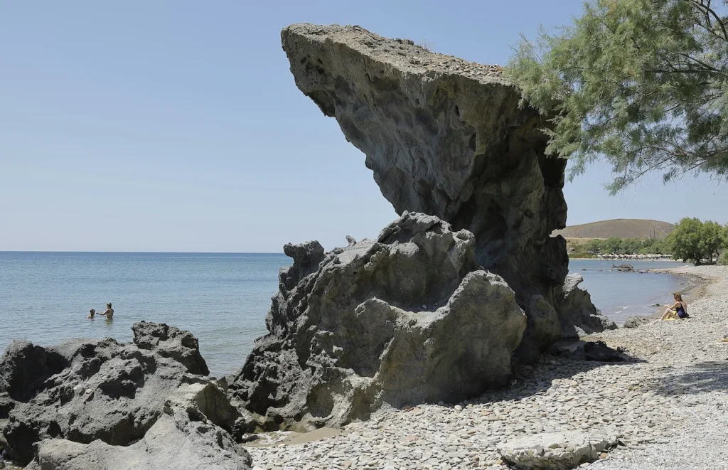 A large volcanic rock formation on the pebbled shore of Agios Ioannis Beach in Lemnos
