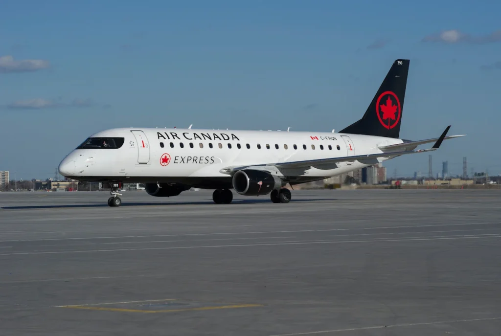 Air Canada Express Embraer 175 regional jet taxiing on a wide concrete airport tarmac