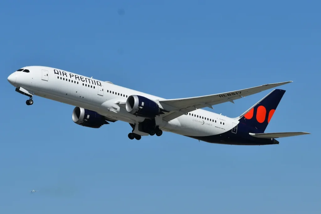 Air Premia Boeing 787-9 Dreamliner commercial passenger airplane ascending into a solid blue sky