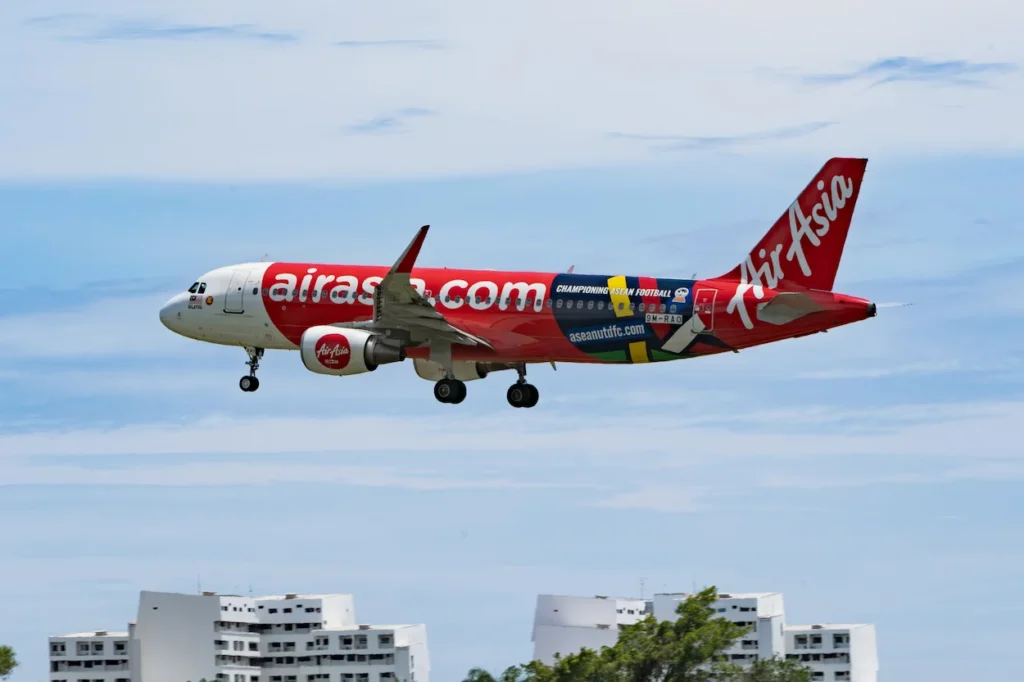 AirAsia Airbus A320 in a special football livery flying over building rooftops