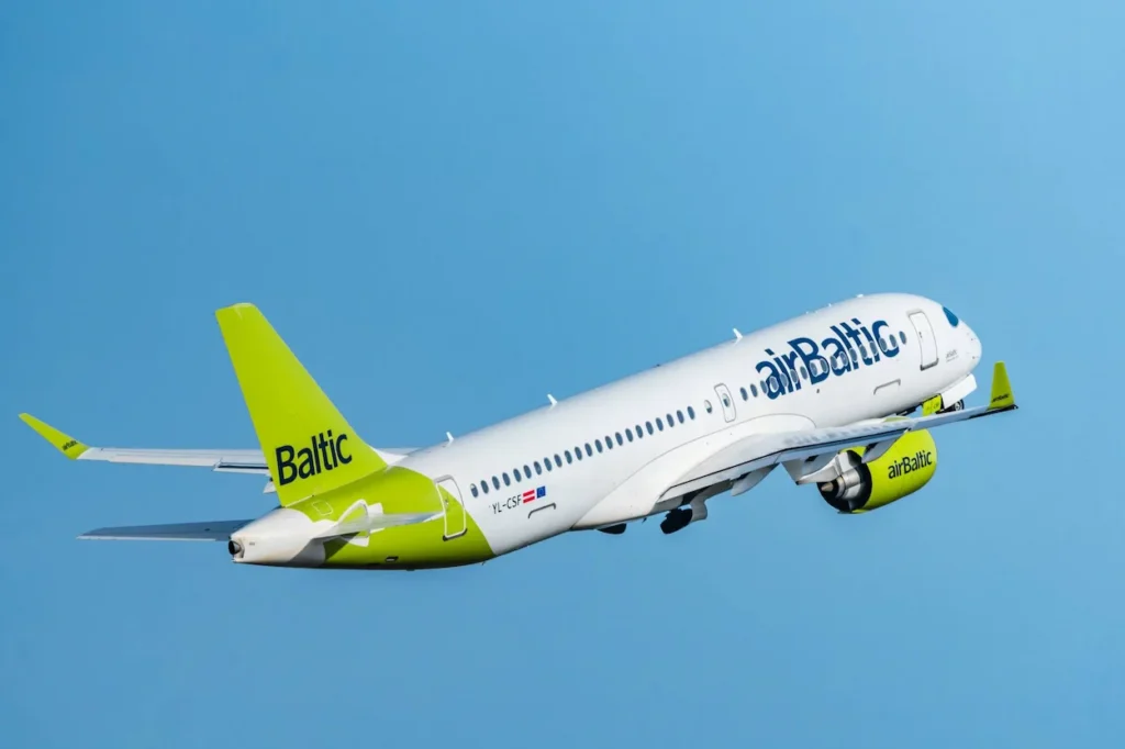 airBaltic Airbus A220-300 with a green tail climbing after takeoff