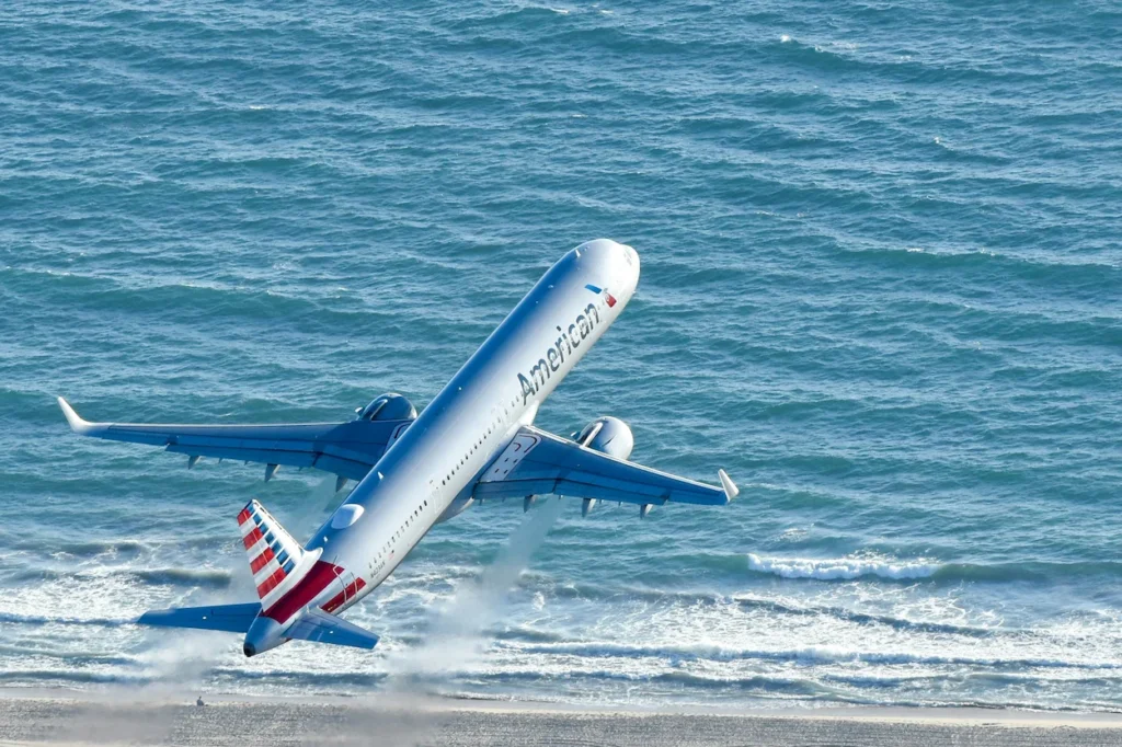 American Airlines Airbus A321 passenger jet climbing sharply over ocean waves immediately after takeoff