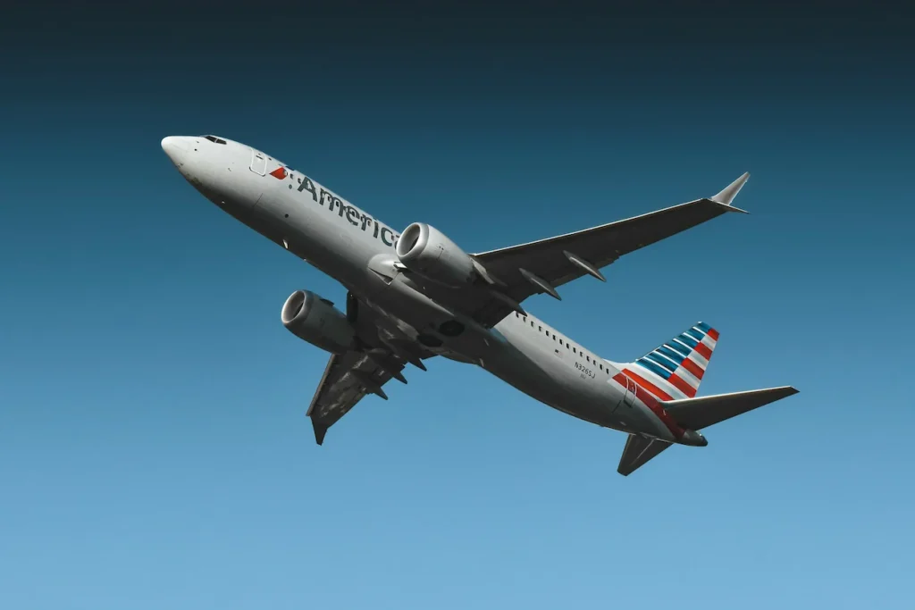 An American Airlines Boeing 737 MAX aircraft climbing sharply against a solid blue sky