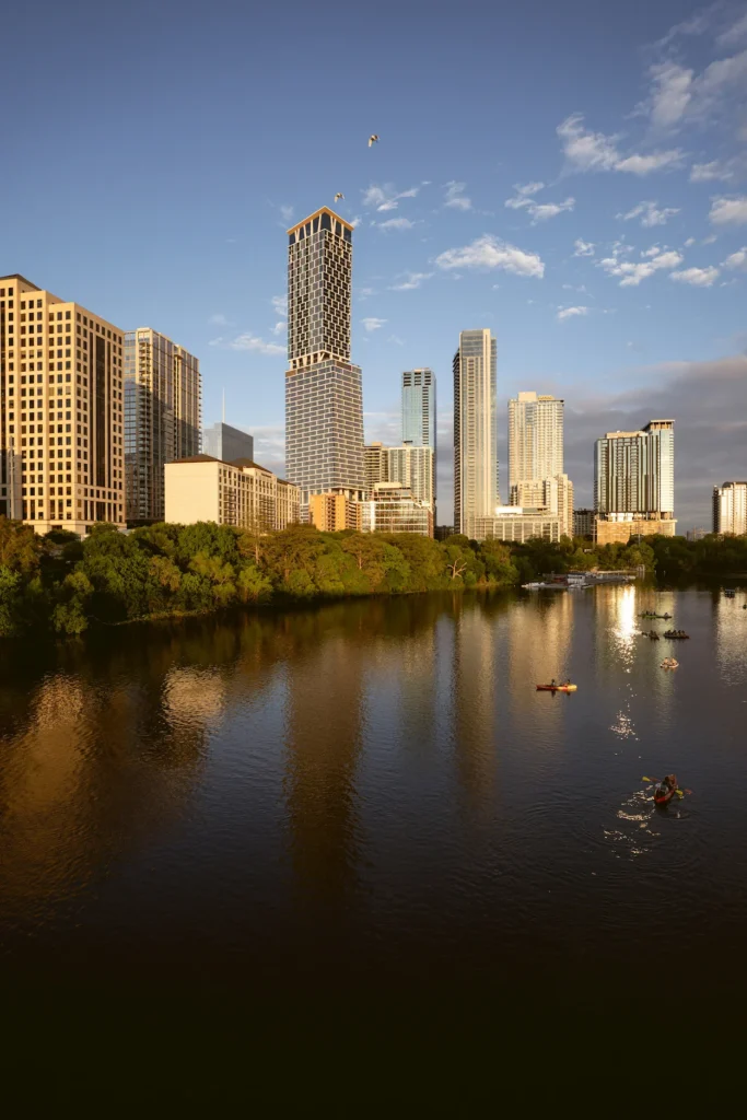 Downtown Austin skyline skyscrapers reflecting on Lady Bird Lake with people kayaking at sunset