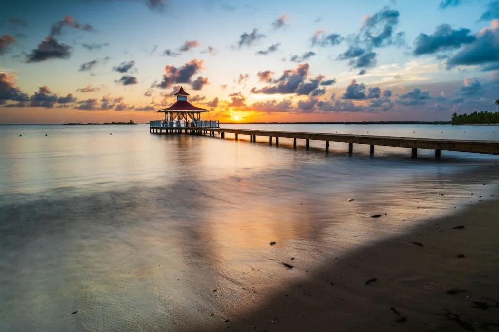 Wooden pier leading to an ocean gazebo at sunset
