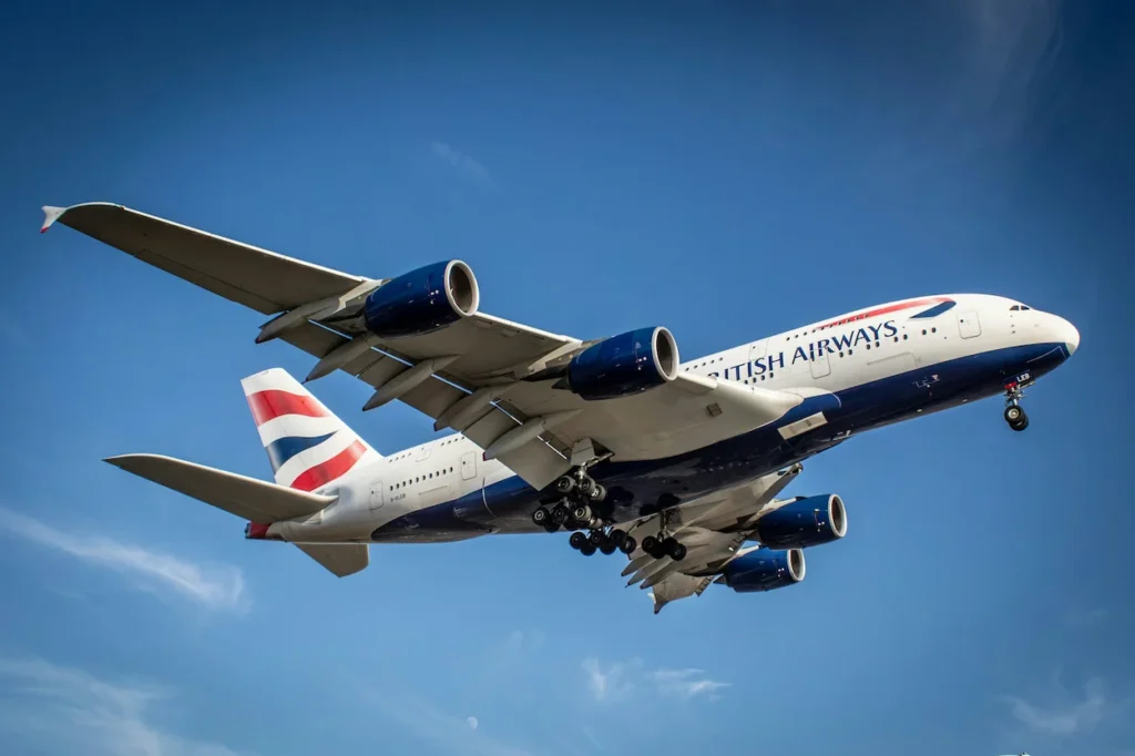 British Airways Airbus A380 double-decker passenger airplane with landing gear down against a blue sky