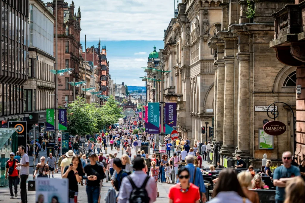 A crowded Buchanan Street in Glasgow lined with historic stone buildings