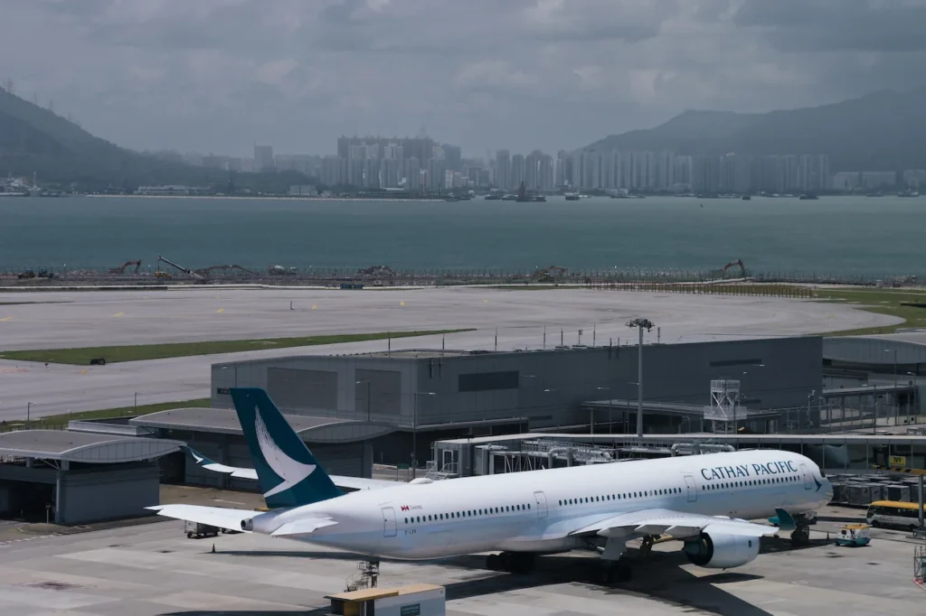 Cathay Pacific Airbus A350 passenger airplane parked at an airport terminal gate next to the water