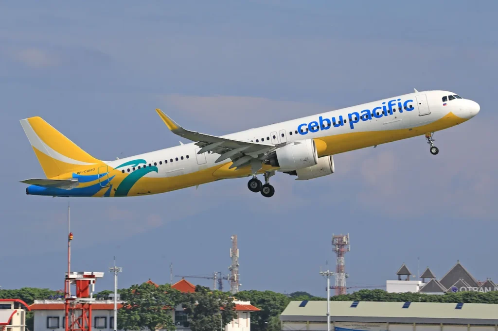 Yellow and blue Cebu Pacific Airbus A321neo passenger airplane taking off into the sky