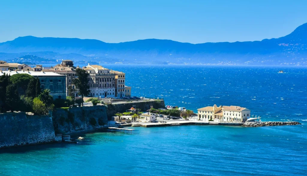 The coastal buildings and turquoise waters of Corfu Old Town under a clear blue sky