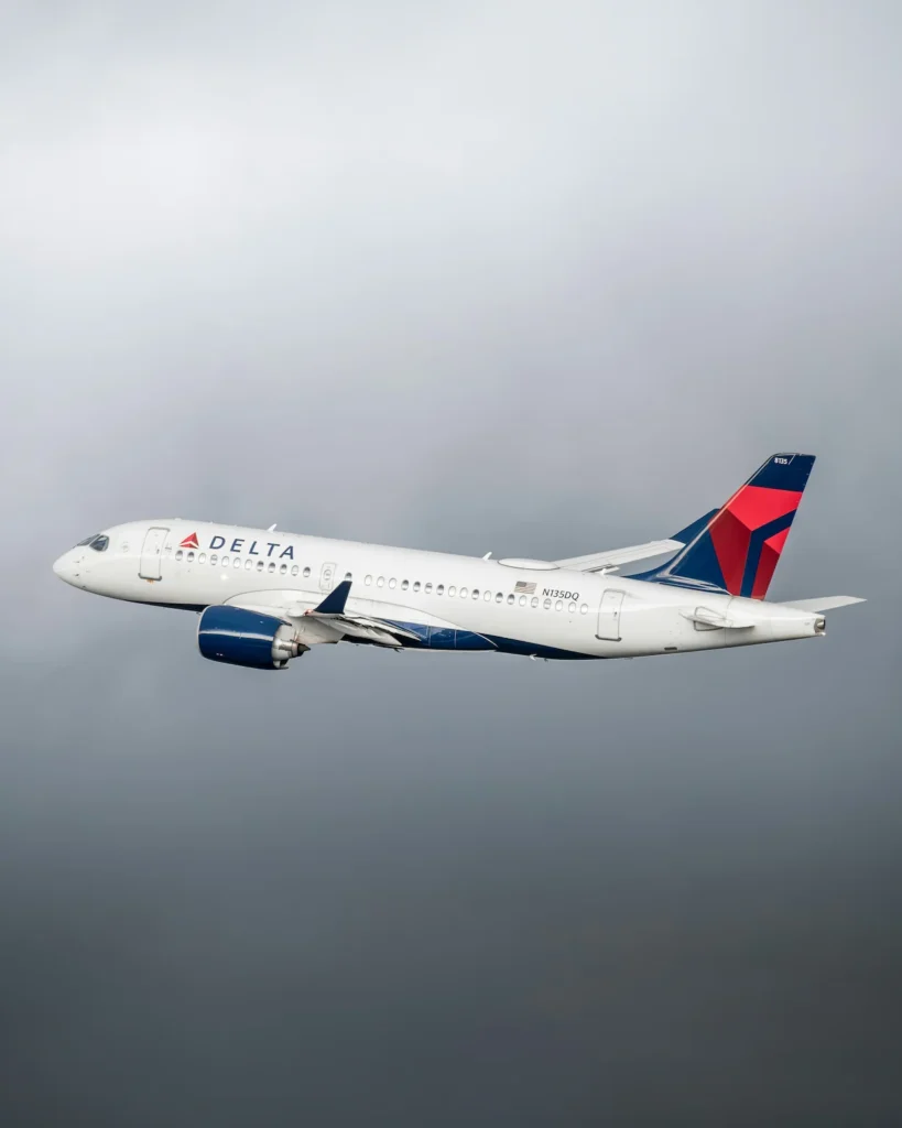 Delta Air Lines Airbus A220-300 airplane registration N135DQ flying in a cloudy sky