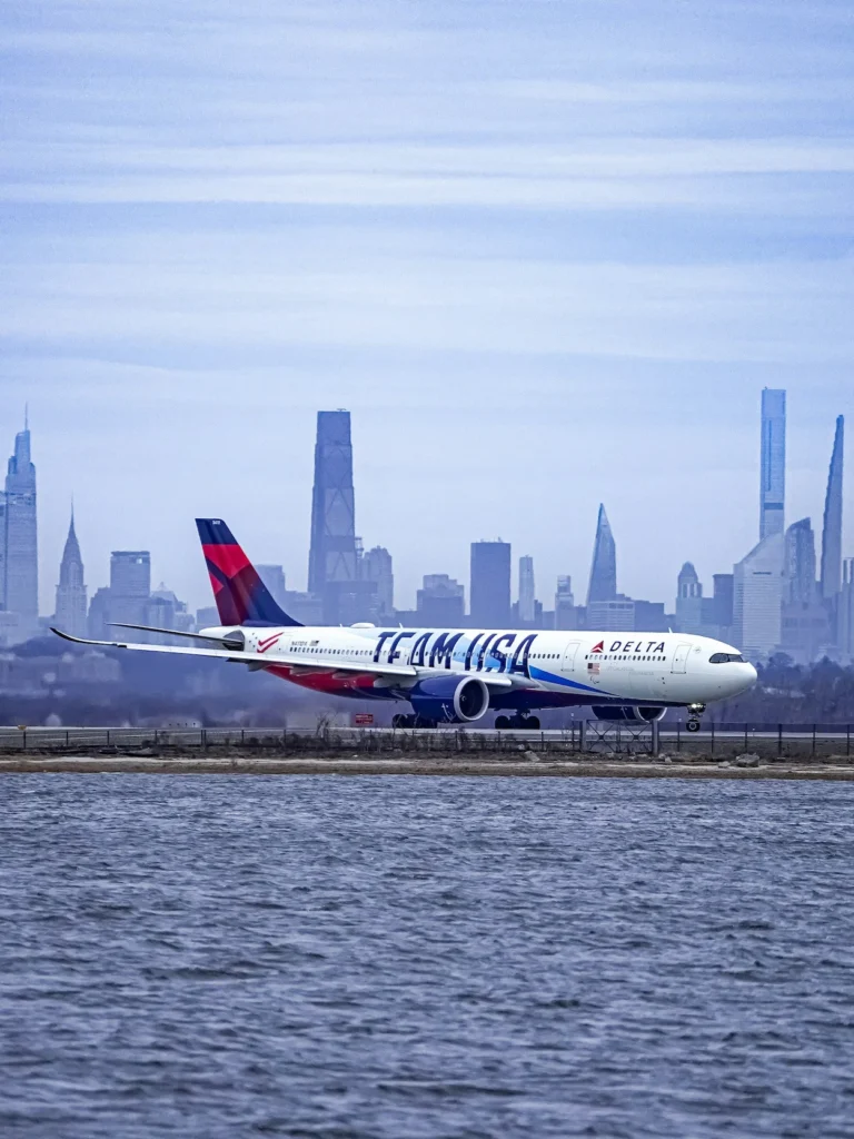 Delta Air Lines Airbus A330neo plane in Team USA livery taxiing on a runway against the New York City skyline