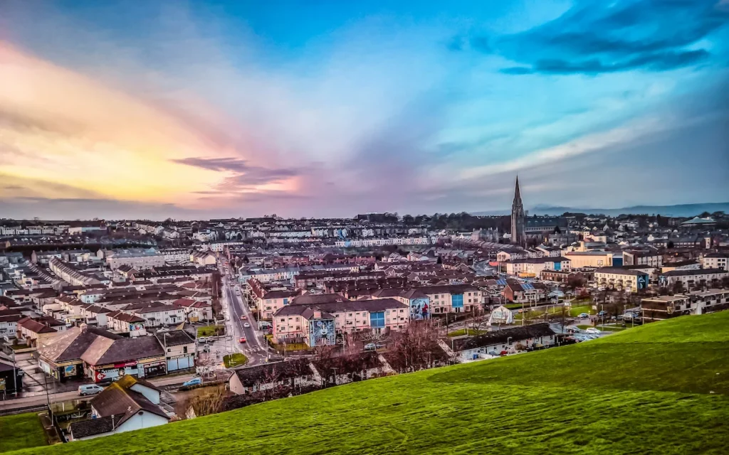High-angle view of Derry city showing St Eugene's Cathedral spire and housing during a dramatic sunset