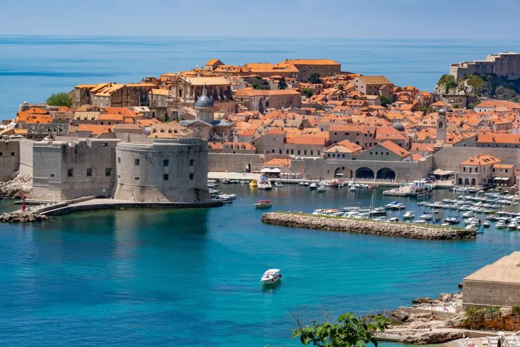 Dubrovnik Old Town stone fortress and harbor filled with boats on the turquoise Adriatic Sea