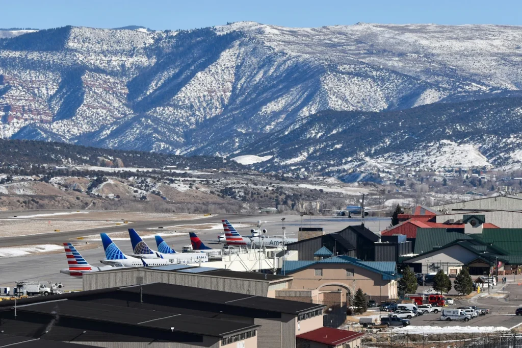 Airplanes parked at terminal gates with snowy mountains behind at Eagle County Regional Airport