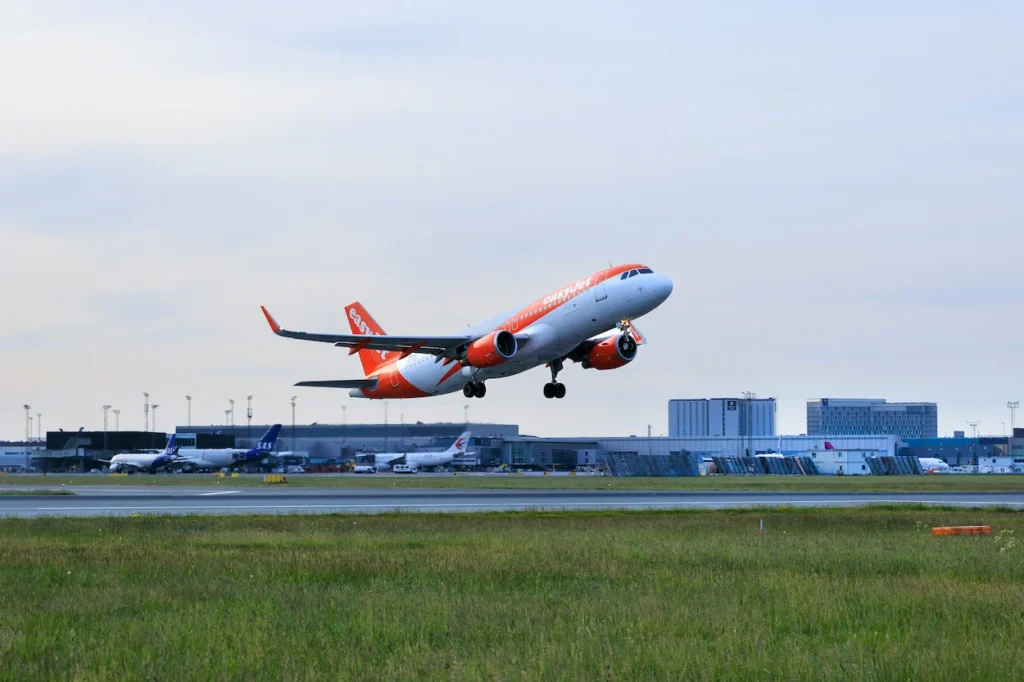 Orange and white easyJet Airbus A320 taking off from a runway
