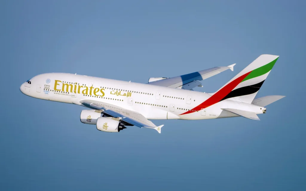 An Emirates Airbus A380 passenger aircraft flying above blue waters