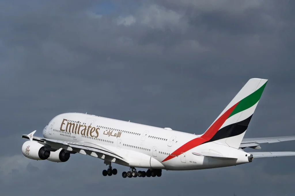 Emirates Airbus A380 airplane flying on a final landing approach against a cloudy grey sky