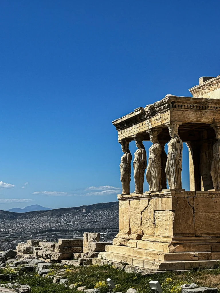 Erechtheion temple on the Acropolis featuring Caryatid statue pillars overlooking the sprawling city of Athens