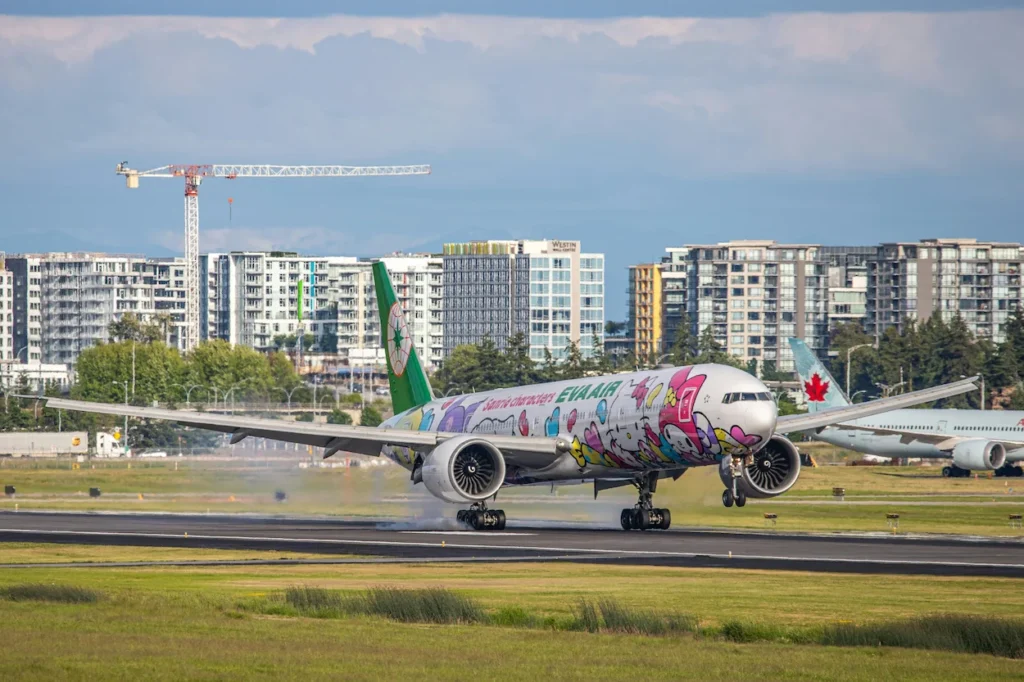 EVA Air Boeing 777 passenger airplane featuring a colorful Hello Kitty Sanrio characters livery landing on an airport runway
