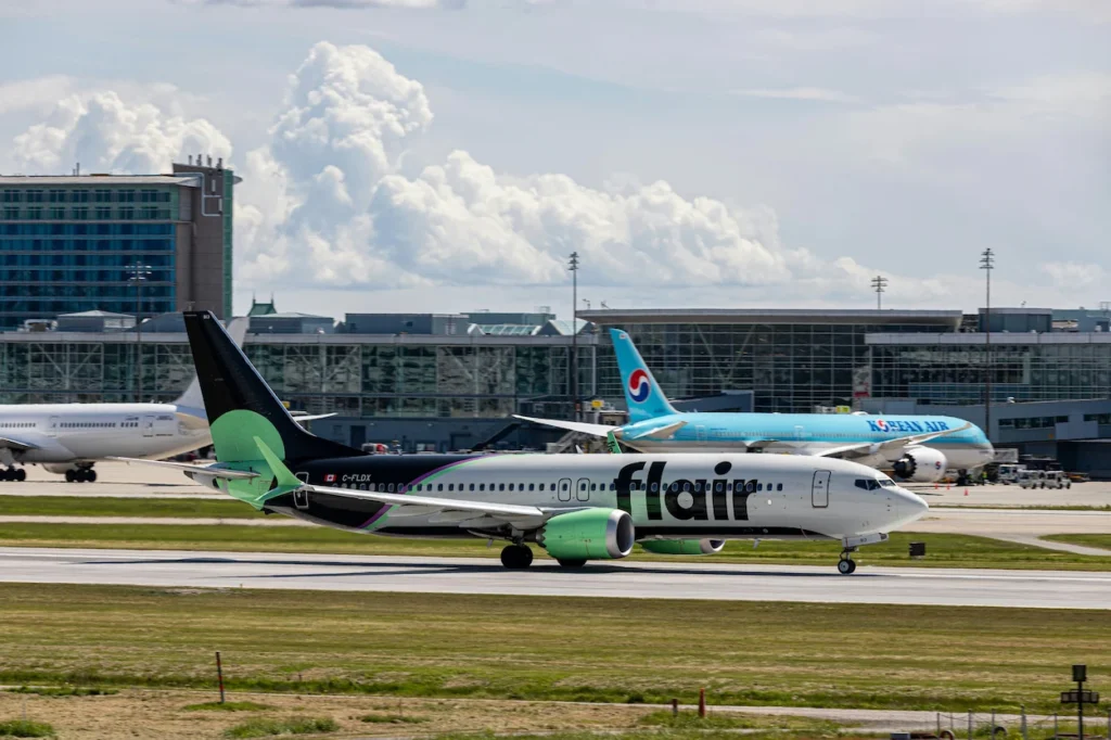 Flair Airlines Boeing 737 MAX 8 taxiing on the airport runway with a Korean Air jet in the background