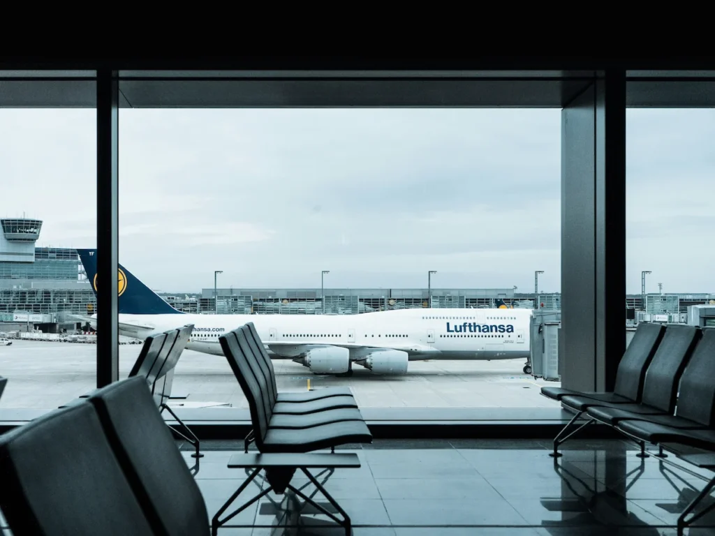 Lufthansa Boeing 747 parked on the tarmac visible through airport terminal windows