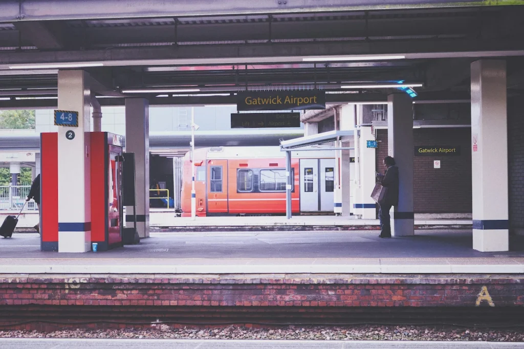 Gatwick Airport train station platform with an orange Gatwick Express train parked across the tracks