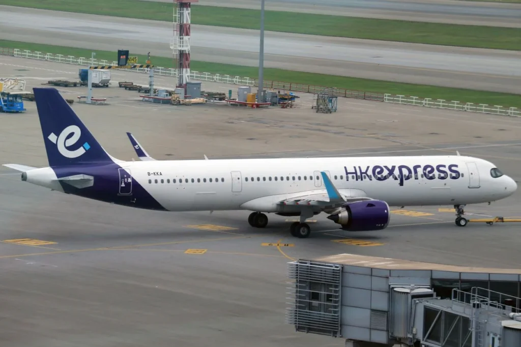A purple and white HK Express Airbus airplane parked on an airport tarmac