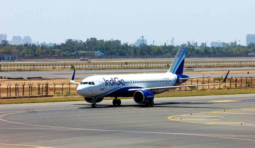 A blue and white IndiGo Airbus passenger plane taxiing on an airport runway