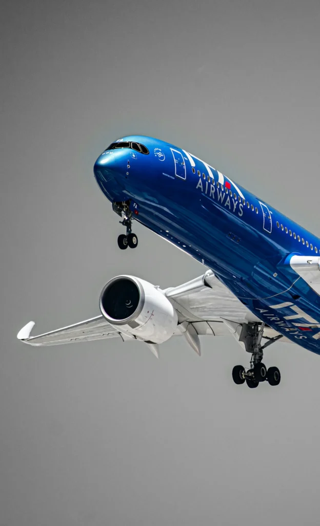 Blue ITA Airways Airbus A350 airplane climbing during takeoff against a gray sky