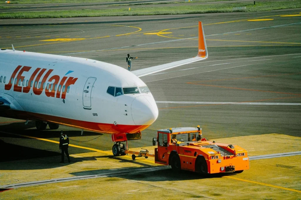 Jeju Air Boeing 737 passenger plane connected to an orange tug vehicle on the airport apron