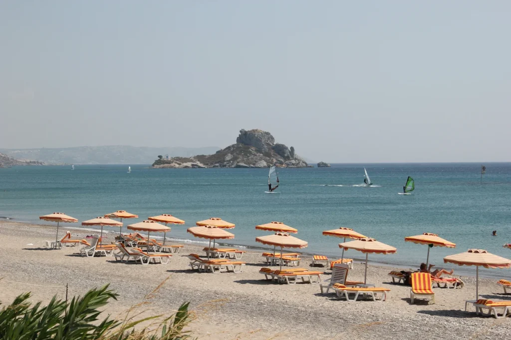 Orange umbrellas on Kamari Beach, Kos, looking toward windsurfers and Kastri Island