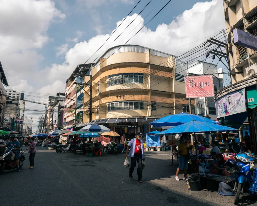 Street market vendors under umbrellas outside shop buildings at Kim Yong Market in Hat Yai, Thailand