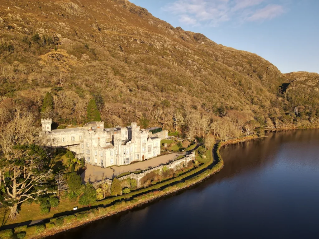 Aerial view of Kylemore Abbey sitting at the base of a mountain along Pollacapall Lough