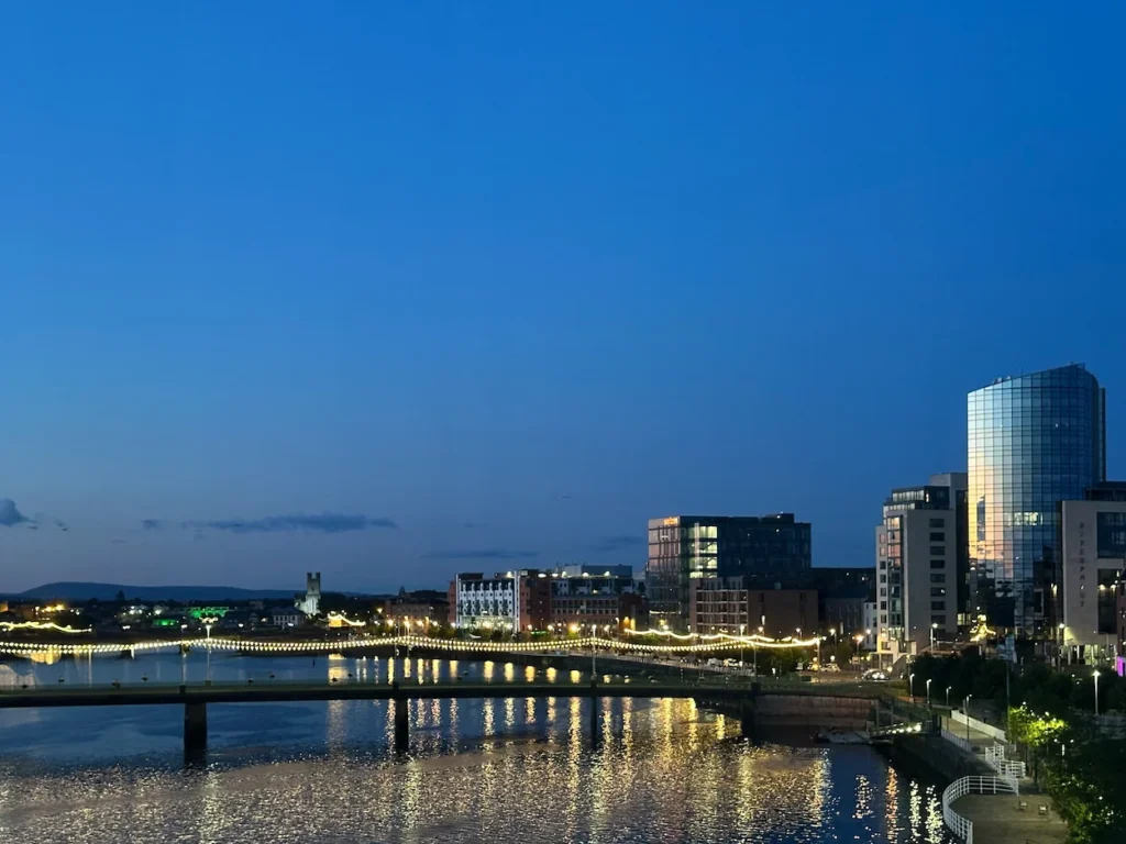 Shannon Bridge and illuminated Riverpoint glass building along the Limerick city skyline at dusk