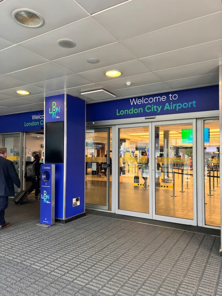 London City Airport glass sliding entrance doors underneath a blue and green welcome sign