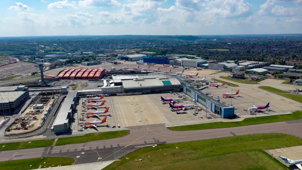 Aerial view of London Luton Airport terminal buildings with parked orange EasyJet and purple Wizz Air airplanes